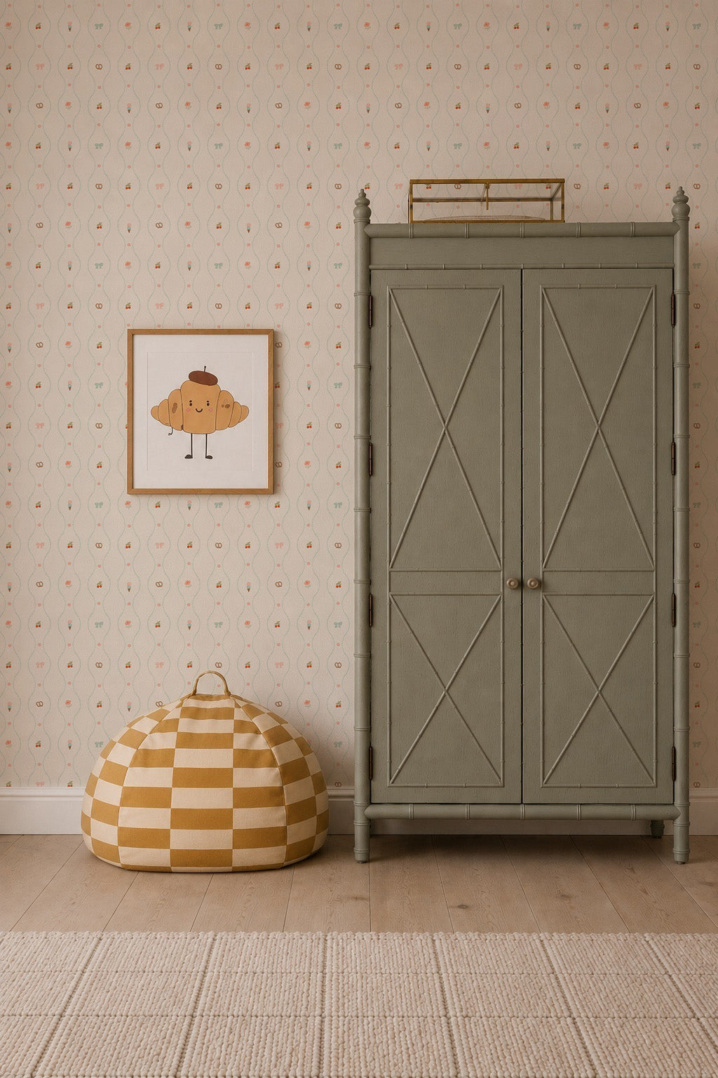 A green wardrobe stands next to a yellow-and-white checkered pouf. Above the pouf hangs a framed illustration of a croissant with arms and legs. The wall is adorned with Little Patisserie Stripe Wallpaper, bringing gentle charm to the playful scene.