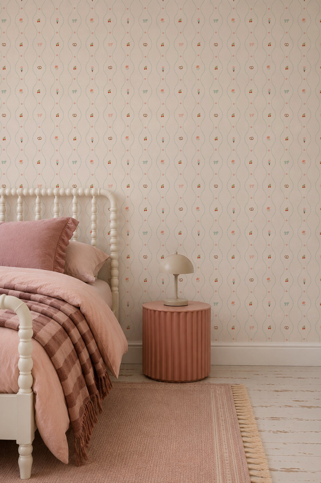 A cozy bedroom featuring a light wooden bed, pink bedding, a round pink nightstand, a small lamp, the charming Little Patisserie Stripe Wallpaper adorning the walls, and a pink rug on a white floor.