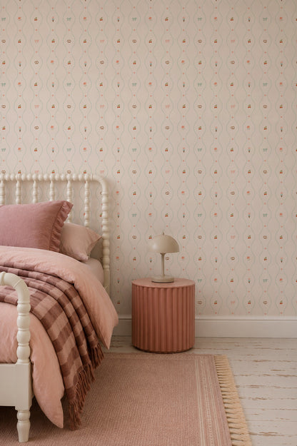 A cozy bedroom featuring a light wooden bed, pink bedding, a round pink nightstand, a small lamp, the charming Little Patisserie Stripe Wallpaper adorning the walls, and a pink rug on a white floor.