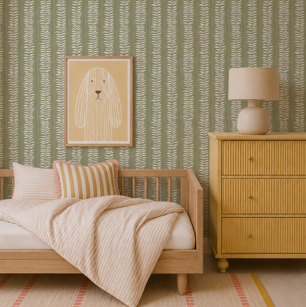 A cozy bedroom with Meadow Leaf Stripe Wallpaper in sage, a light wood bed with botanical stripe bedding, a yellow dresser with a lamp, and a framed dog print—perfect for charming nursery decor.