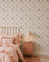 A cozy bedroom featuring Mermaid Friends Wallpaper, a ruffled pink bedspread with matching pillows, and a pink nightstand topped with a round lamp for a charming, playful look.