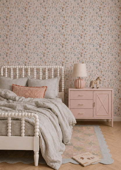 A cozy bedroom features a light wood bed, soft gray bedding, and pastel decor. Millie Floral Wallpaper and a pink nightstand add gentle charm, while a toy giraffe rests beneath the warm glow of a pink lamp.