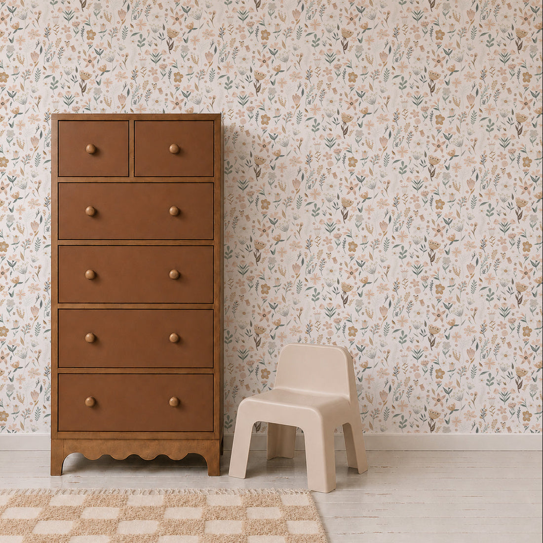 A brown wooden dresser with six drawers stands next to a small beige plastic chair, set against the elegant Millie Floral Wallpaper, which showcases a delicate floral repeat pattern. A beige rug is partially visible in the foreground, complementing the light floor.