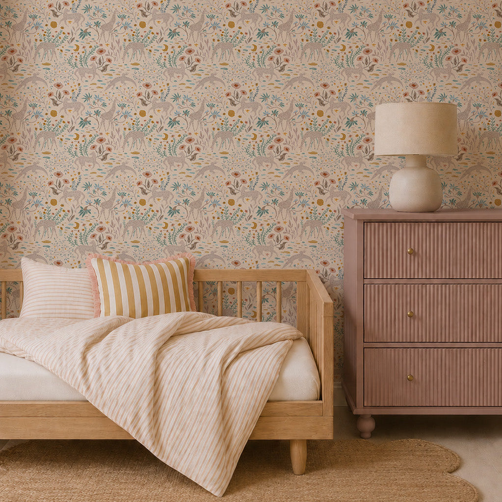 A cozy bedroom featuring a wooden daybed, striped pillows and blanket, a scalloped beige rug, a mauve dresser with a lamp, and elegant Mils Menagerie Wallpaper in Rose with soft pastel floral patterns.