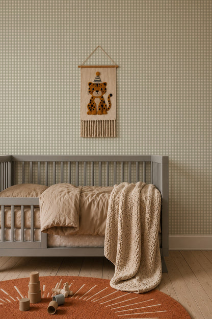 A grey crib with beige bedding and a knitted throw blanket sits against Mini Check Wallpaper, Green, featuring a felt leopard wall hanging above it and a round rug on the floor.