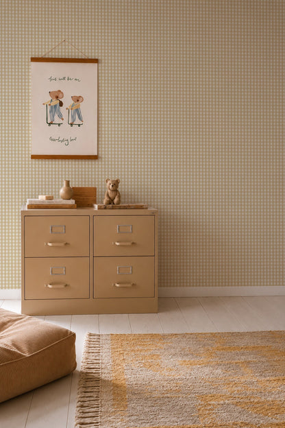 A beige four-drawer filing cabinet sits against Mini Check Wallpaper, Yellow, topped with a small teddy bear, a wooden vase, and stacked books beneath a framed illustration of two bears on skateboards.
