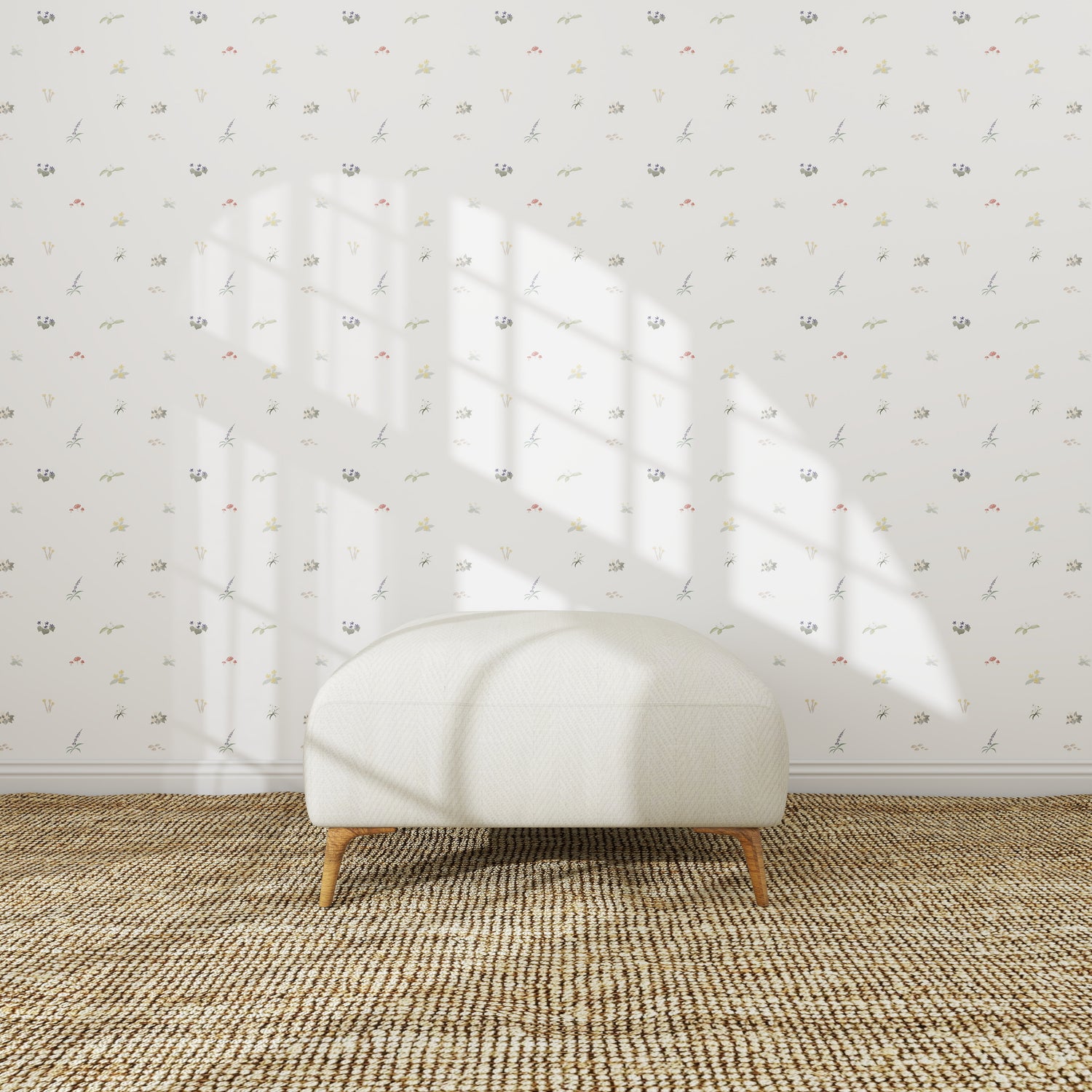 A simple white ottoman sits on a woven rug in front of a white wall adorned with Mollys Flower Garden Wallpaper Repeat | Sample. Sunlight streams in, casting a window-shaped shadow above the ottoman.