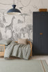 A child’s room with a wooden bed, plaid bedding, gray wardrobe, and the Paradise Jungle Mural, Monochrome featuring illustrated safari animals. A woven basket on the wardrobe adds charm to the children’s decor.
