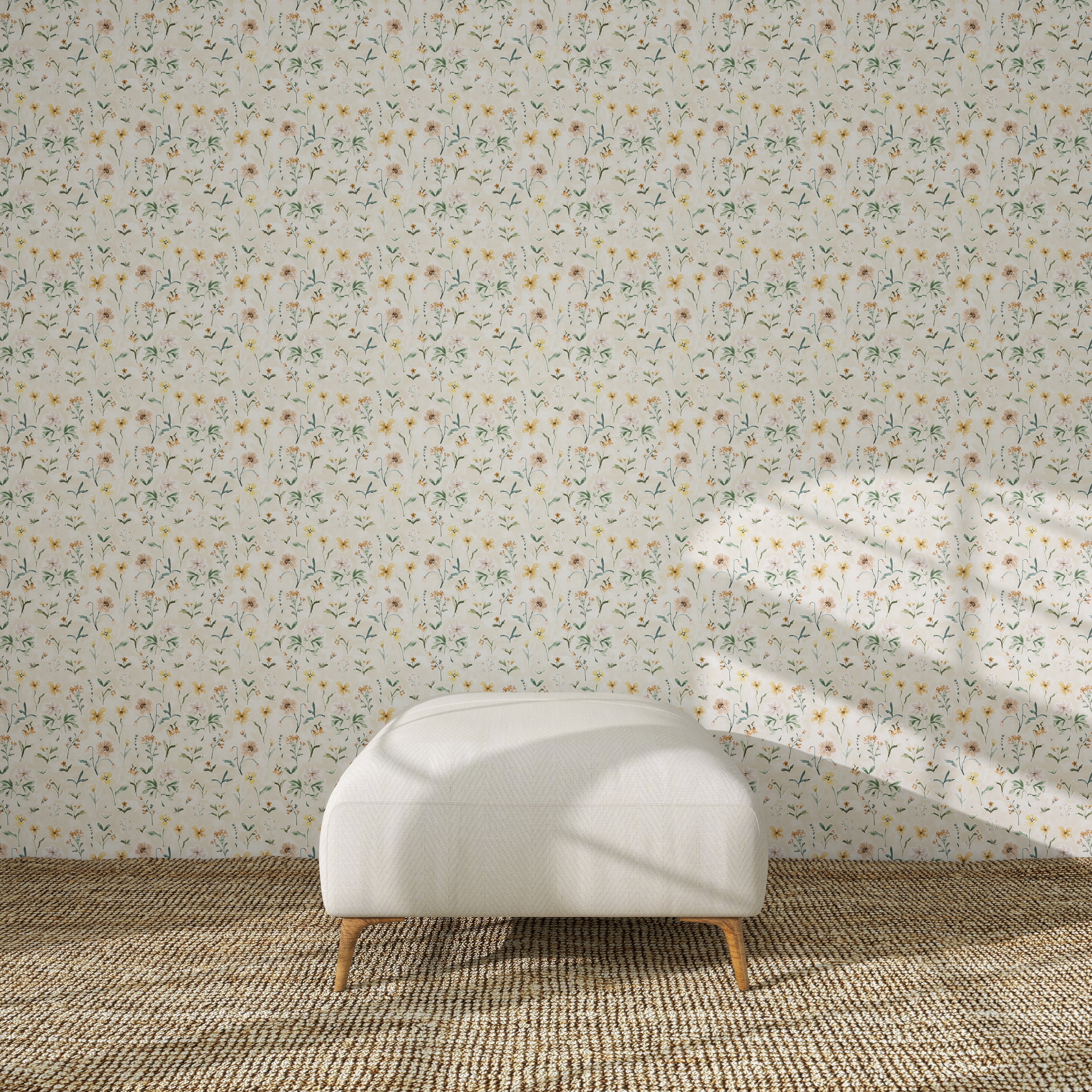 A white ottoman with wooden legs sits on a woven rug before a wall decorated with Morning Meadow Wallpaper, as sunlight casts gentle window shadows across the scene.