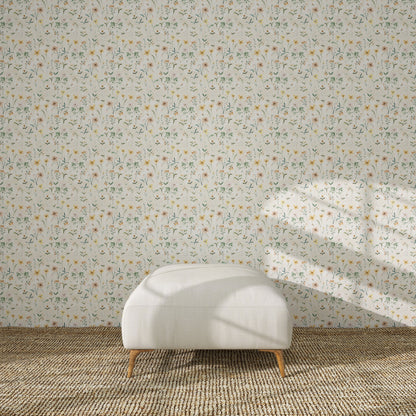 A white ottoman with wooden legs sits on a woven rug before a wall decorated with Morning Meadow Wallpaper, as sunlight casts gentle window shadows across the scene.