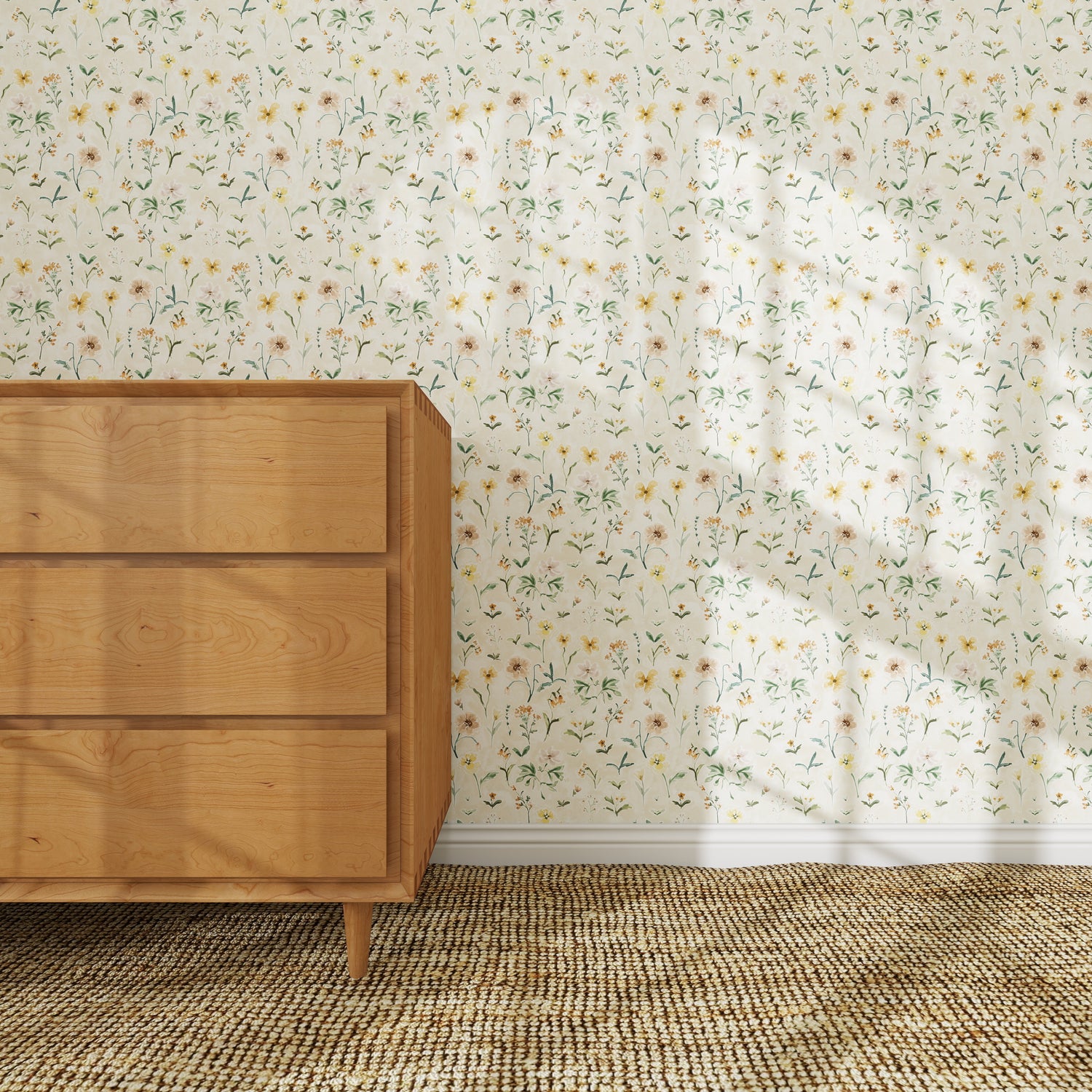 A wooden dresser stands on a woven rug against a wall decorated with Morning Meadow Wallpaper. Sunlight pours in through the window, casting gentle shadows on the hand-painted wallpaper and the floor below.