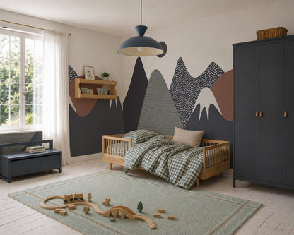 A cozy kids’ bedroom with a wooden bed, checkered bedding, Mountain Mural wall art, dark wardrobe, green rug scattered with wooden toys, bench, and window with sheer curtains welcoming sunlight—a true mountain oasis in home decor.