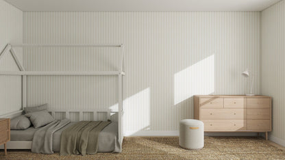 A minimalist bedroom features a house-shaped bed frame, neutral bedding, wooden dresser, nightstand, and walls adorned with Little Abacus Stripe Off White and Taupe Wallpaper, all enhanced by soft-toned rugs and abundant natural light.