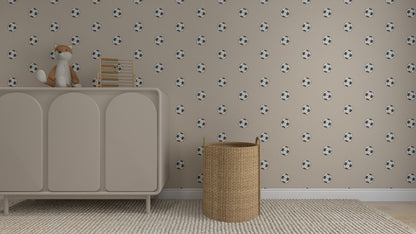A nursery room features the Its All About Footballs Repeat Pattern beige wallpaper, a light dresser with a plush fox and abacus, a woven basket, and a textured rug—perfect for little sports fans.