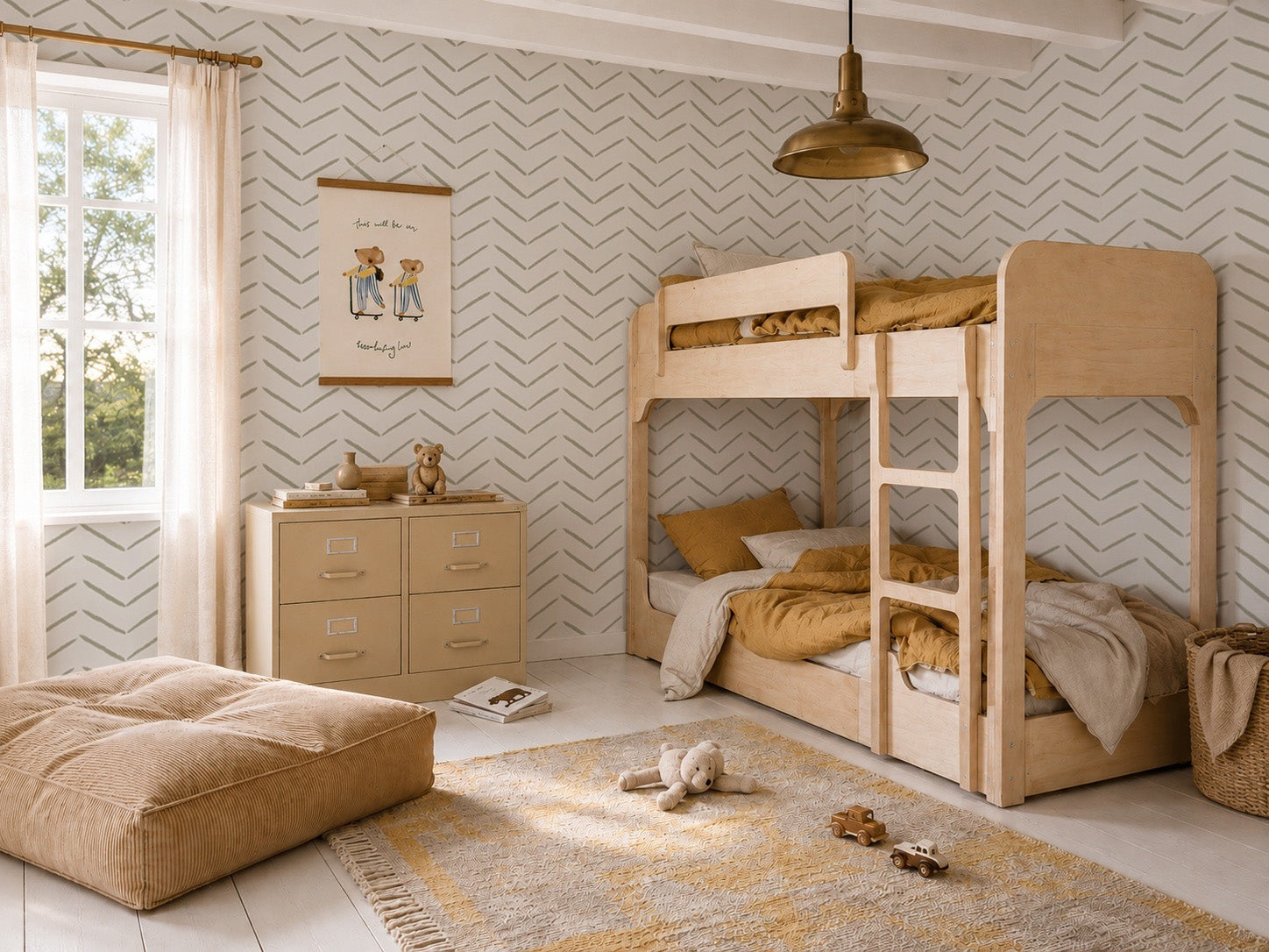 A cozy kids bedroom with bunk beds, a dresser, a plush floor cushion, toys on a rug, and a large window with sheer curtains. The room features neutral tones and stylish wall decor complemented by Herringbone Wallpaper in Olive.