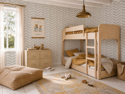 A cozy kids bedroom with bunk beds, a dresser, a plush floor cushion, toys on a rug, and a large window with sheer curtains. The room features neutral tones and stylish wall decor complemented by Herringbone Wallpaper in Olive.