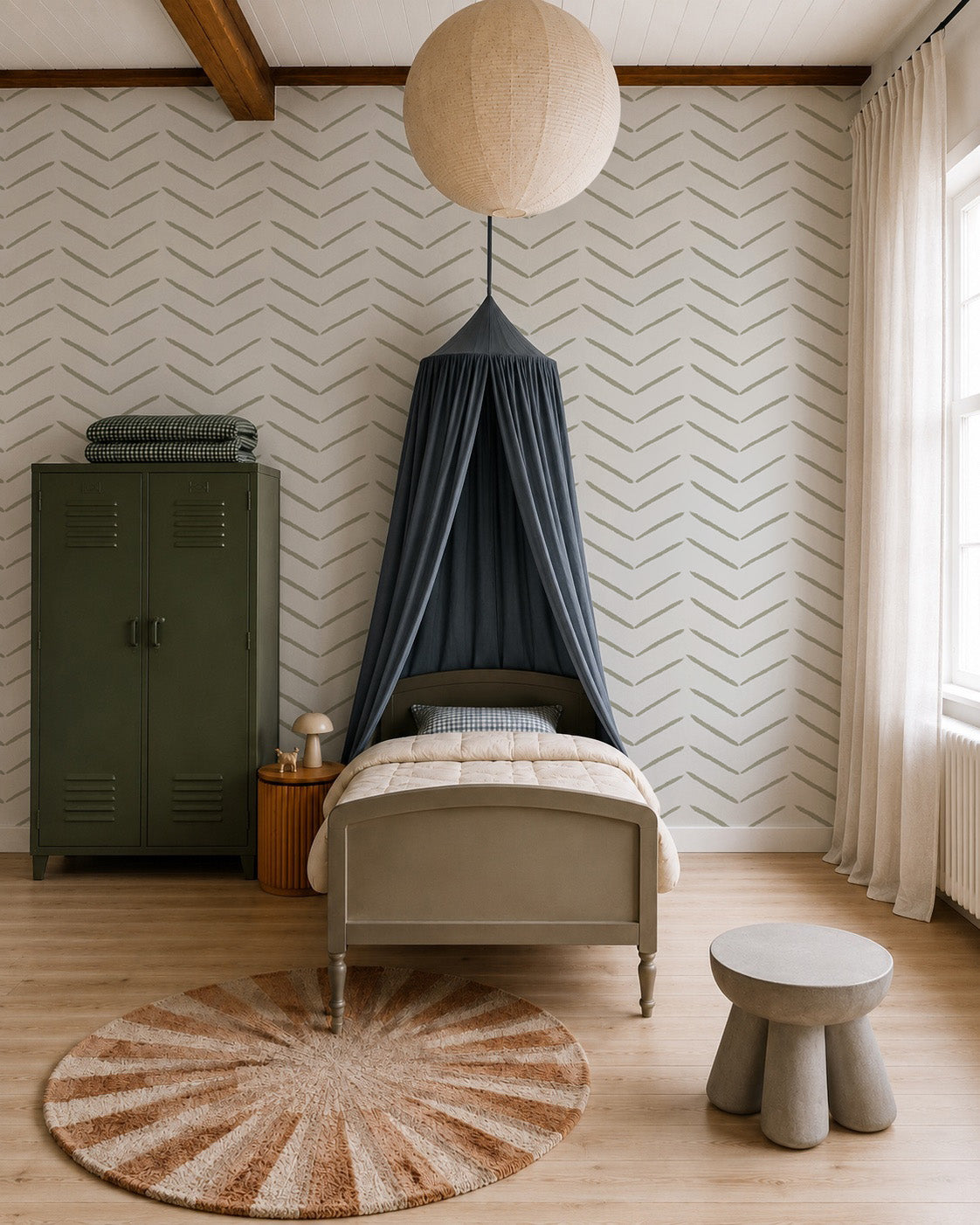 A cozy, modern bedroom with a single bed under a navy canopy, an olive green locker, round rug, small gray table and stool, and stylish wall decor featuring Herringbone Wallpaper in Olive, all lit by natural light from a window with sheer curtains.