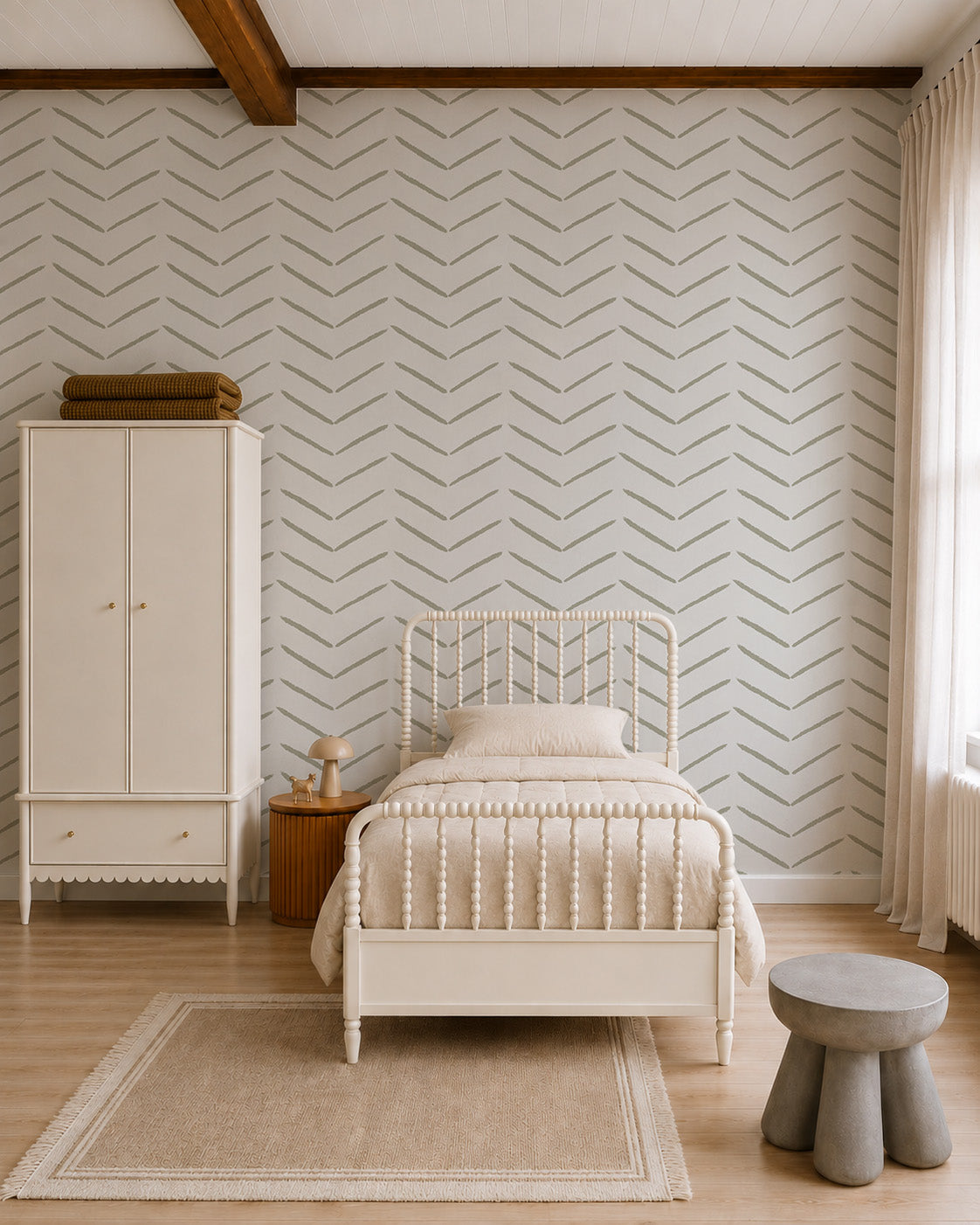 A cozy bedroom features a cream-colored bed, matching wardrobe, small nightstand with lamp, round stool, and a large window. The wall is adorned with Herringbone Wallpaper in Olive as elegant decor. Neutral tones and natural light create a calm atmosphere.