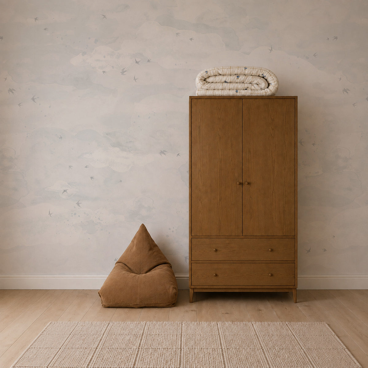 A wooden wardrobe and a triangular beanbag chair stand against a wall covered in Opals Sky Birds Mural, Salt wallpaper.