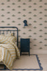 A cozy bedroom features a blue metal bed with yellow-striped bedding, a blue nightstand, a blue wall lamp, and Otis Dinosaur Wallpaper—perfect for playful home decor.