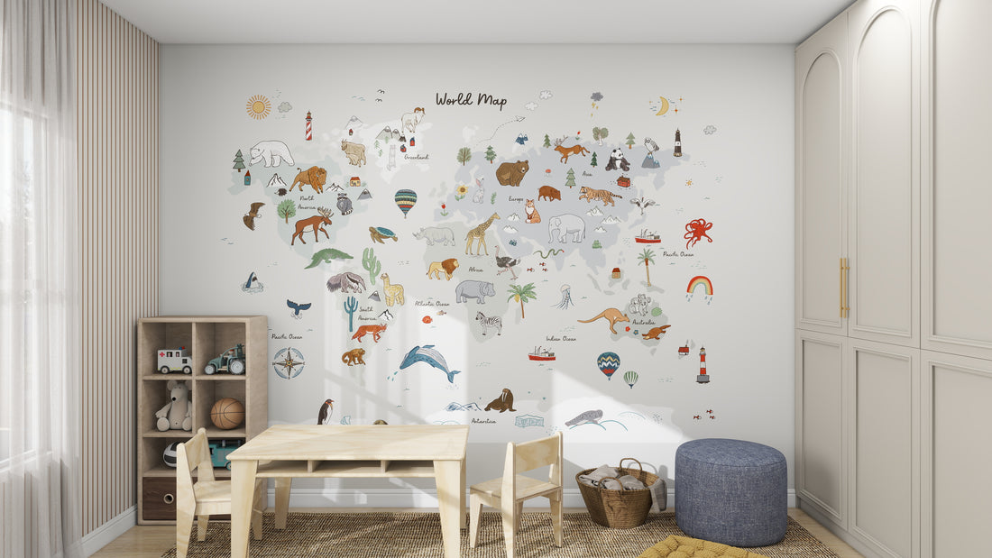 The playroom features a wooden table, chairs, a blue pouf, and toys. The walls come alive with the munks and me World Map Wallpaper Mural in Grey adorned with animals and landmarks. Light striped curtains and cabinets complete the charming setting.