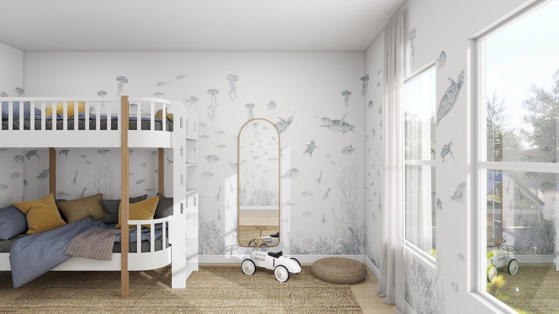 A cozy childrens room features a white bunk bed with gray and yellow bedding. The Fish Tank Wallpaper Mural in blue by munks and me adds an ocean charm, teeming with vibrant sea creatures. A tall mirror and toy car are near a large window, with a woven rug on the floor.