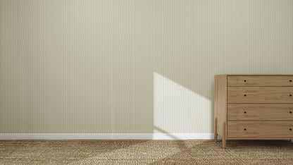 A minimalist room features Pico Stripe Wallpaper Green, a woven brown carpet, and a wooden dresser on the right. Sunlight creates geometric shadows across the wall and floor.