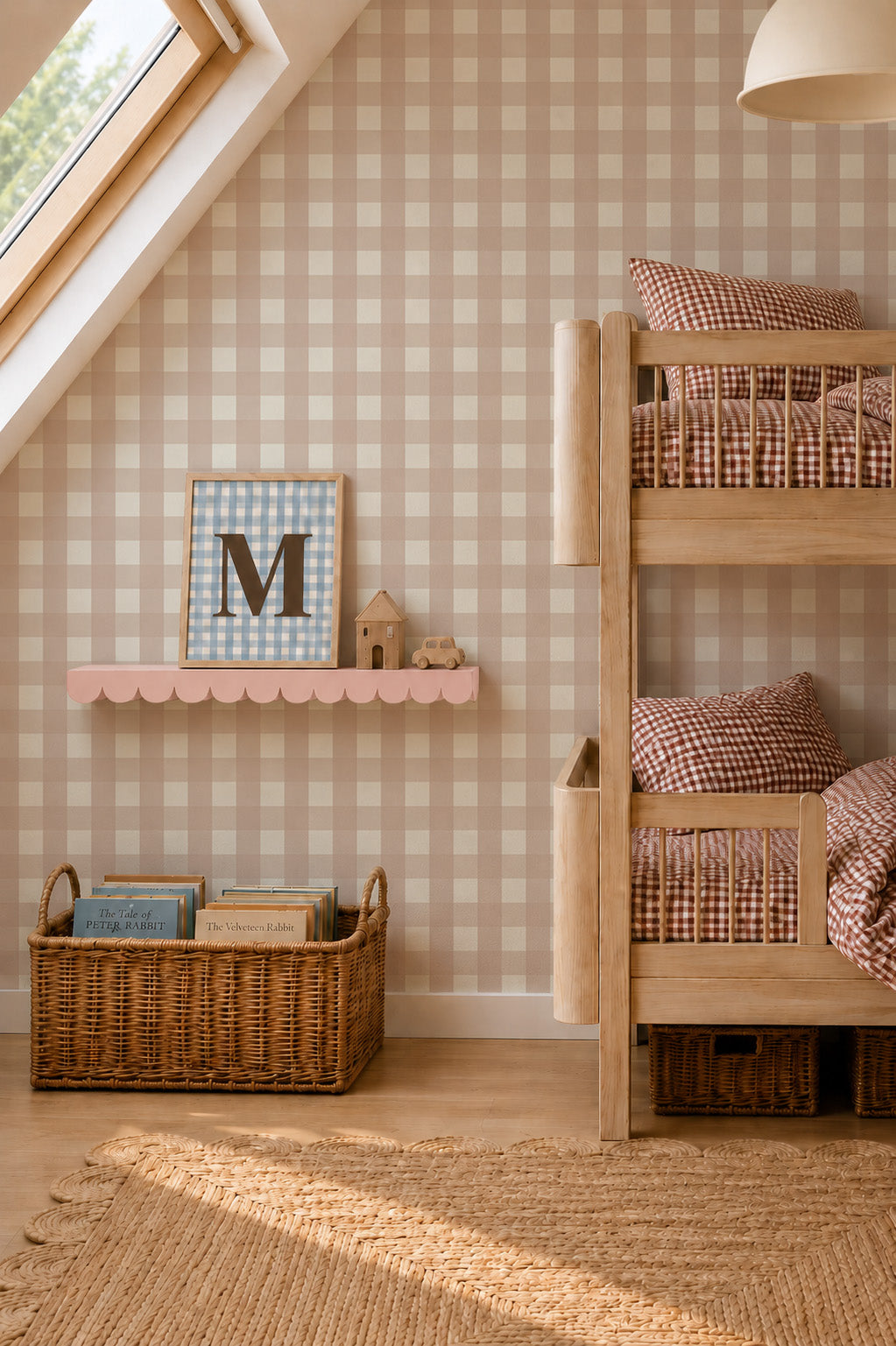 A child’s bedroom featuring a wooden bunk bed with gingham bedding, a scalloped shelf holding a framed letter M and wooden toys, and a basket of books resting against Large Check Wallpaper Sample, Pink.