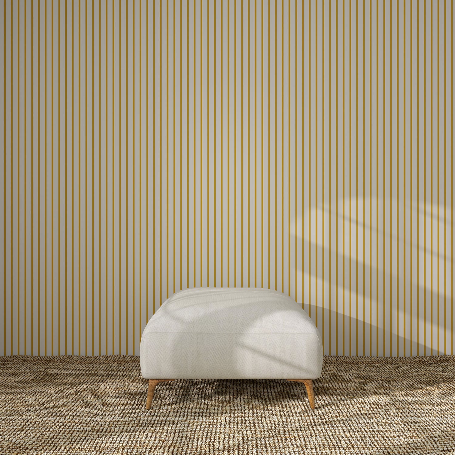 A minimalist room features a beige ottoman on a textured carpet, set against a wall with Pinstripe Wallpaper Mustard. Sunlight streaming through an unseen window casts soft shadows, adding warmth to the modern nursery decor.
