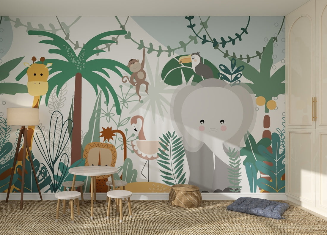 A children’s playroom features Safari Wallpaper | Sample in vibrant jungle colors with cartoon animals like an elephant, giraffe, and toucan. Small tables, chairs, wicker baskets, and cushions on a woven rug enhance the wallpaper’s quality.