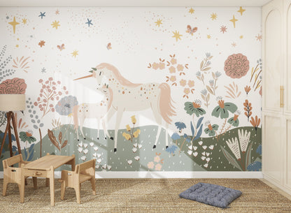 A children’s room featuring the Unicorn Meadow Wallpaper Mural, showing two unicorns among colorful flowers, leaves, and stars. The space includes a small wooden table with chairs, a blue floor cushion, a lamp, and built-in white cabinets.