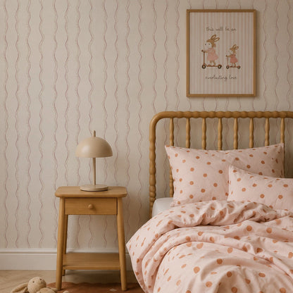 Elegant children’s bedroom featuring a wooden bed with polka dot bedding, a bedside table with a lamp, a stuffed bunny on a brown rug, and framed art displayed on Ribbon Stripe Wallpaper in Rose for a sophisticated touch.