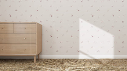 A light wood dresser with four drawers stands on a woven tan rug by a wall decorated with Ruffles Bull Dog Wallpaper Repeat Pattern | Rose. Sunlight casts a triangle-shaped shadow, adding charm to the cozy scene.