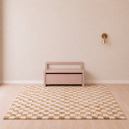 Minimalist room with a pink bench, patterned rug in beige and white checks, small dotted nursery wallpaper, and a single gold wall sconce on the right—beautifully complemented by the Scallop Shell Mural in Pink for a subtle coastal nursery décor.