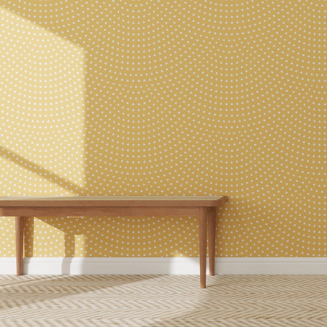A wooden bench rests against a wall covered in Scallop Shell Wallpaper Yellow | Sample. Sunlight casts shadows, while a chevron rug on the wooden floor creates an inviting space inspired by online imagery.