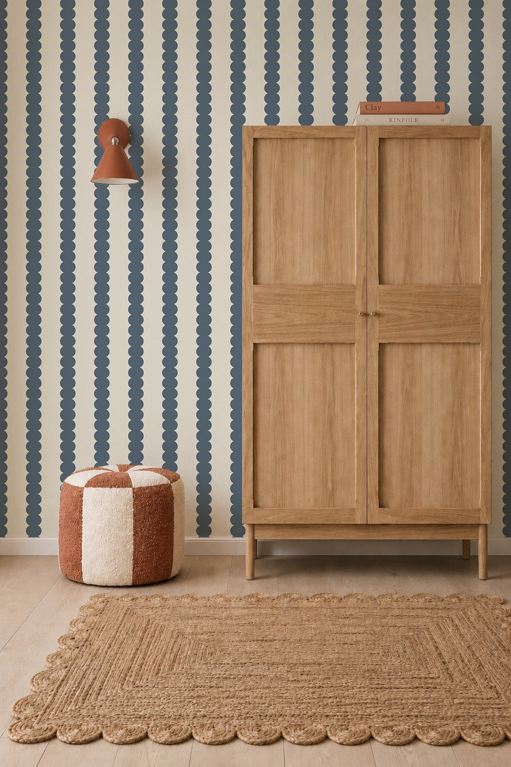 A room featuring Scallop Stripe Wallpaper, Deep Blue in deep blue against an off-white background, complete with a wooden cabinet, a checkered ottoman, and a textured area rug.
