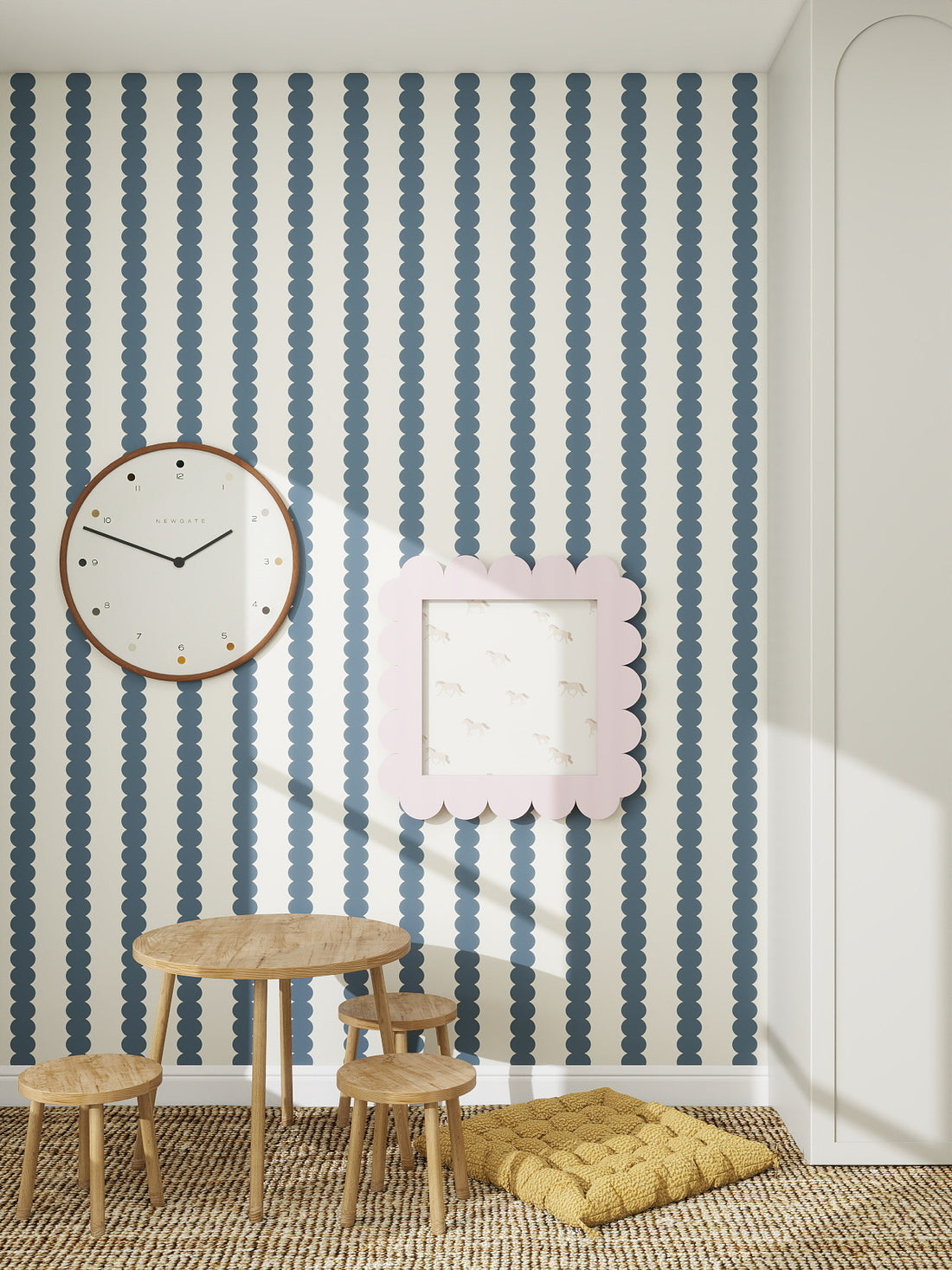 A children’s playroom with a small wooden table and stools, a yellow floor cushion, a large wall clock, a framed picture, and Scallop Stripe Wallpaper Deep Blue—ideal for creating a cozy nursery atmosphere.