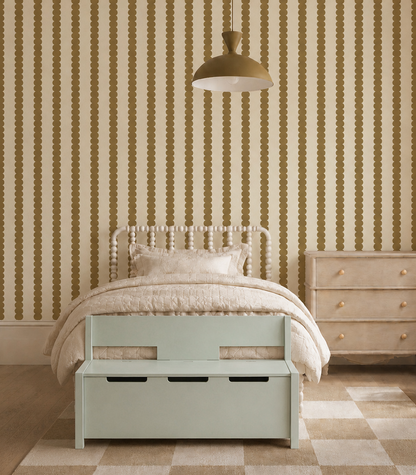 A cozy bedroom with Scallop Stripe Wallpaper in moss, a cream bed with textured bedding, a pastel green storage bench, wooden dresser, geometric rug, and a gold pendant lamp overhead.