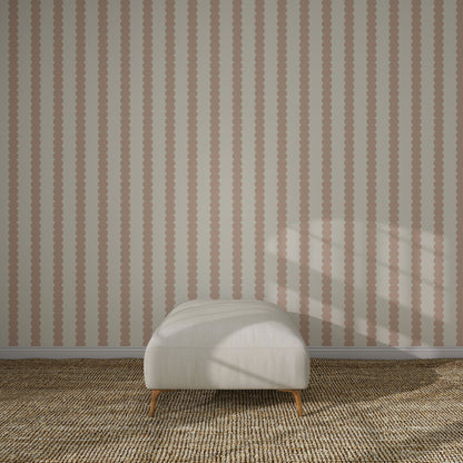 A white cushioned ottoman sits on a textured beige carpet in front of Scallop Stripe Wallpaper Pink. Sunlight casts soft shadows across the scene.