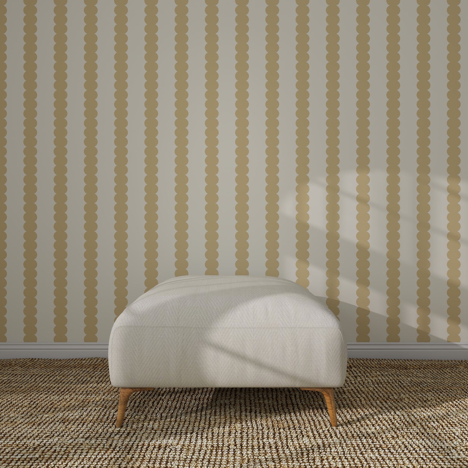 A white cushioned ottoman with wooden legs sits on a woven rug before a beige wall decorated with Scallop Stripe Wallpaper Sample, Yellow, its vertical scalloped stripes highlighted by sunlight casting shadows on the scene.