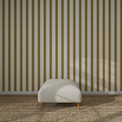 A minimalist room features a white cushioned ottoman on a brown patterned carpet, set against a wall adorned with Scallop Stripe Wallpaper Sample, Moss. Sunlight casts shadows across the ottoman and the striped wallpaper.