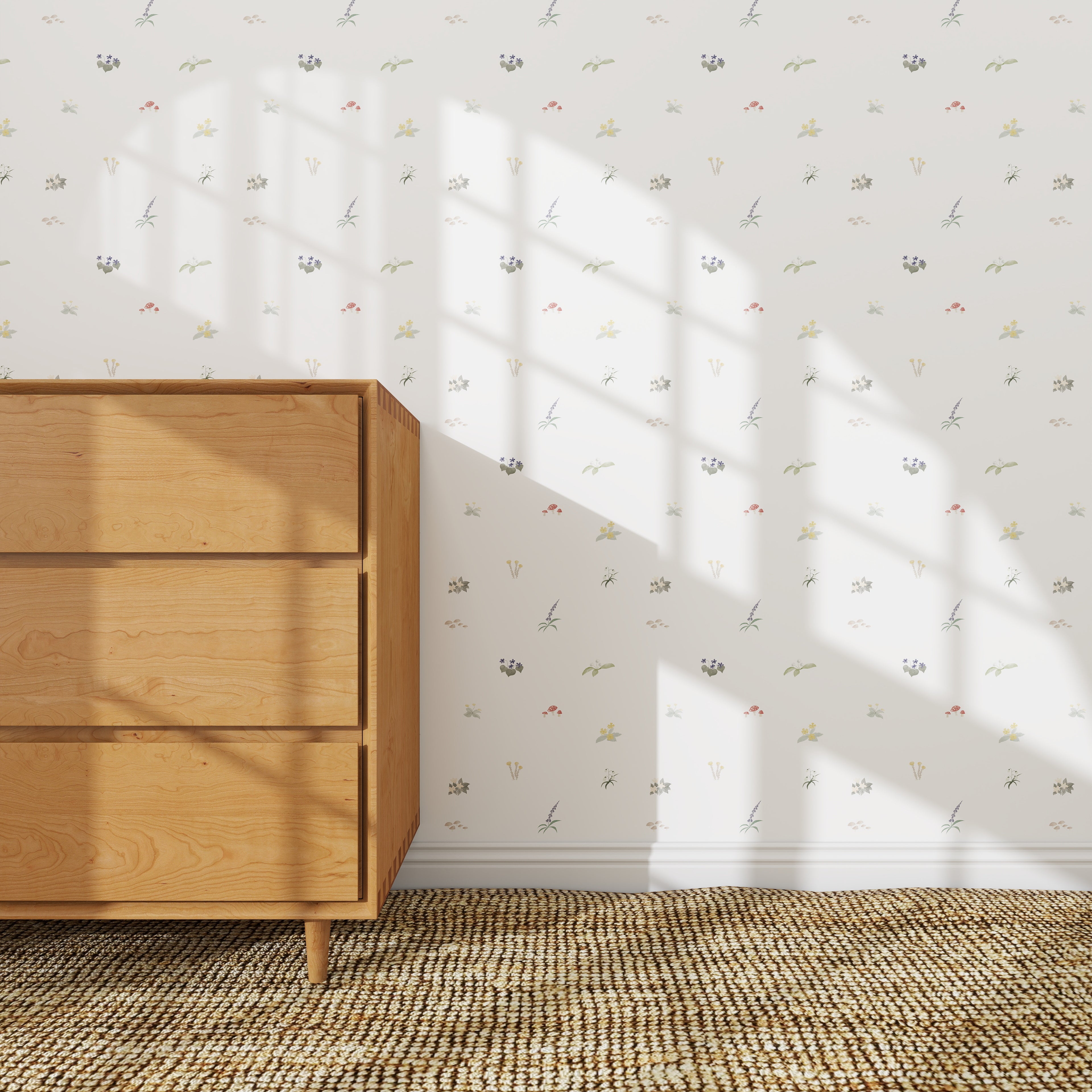 The Mollys Flower Garden Wallpaper Repeat | Sample adds a delicate floral touch to the white wall behind a light wooden dresser, with sunlight casting windowpane shadows across both the wallpaper and dresser for an inviting look.