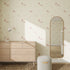 A minimalist bedroom features light wood furniture, a tall arched mirror, and walls adorned with the Custom Puppy Dog Wallpaper Repeat Pattern in Rose. Sunlight filters in, highlighting chic decor accents and playful puppy illustrations.