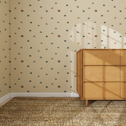A light wood dresser sits in the corner of a room with beige walls decorated in Transport Trail Wallpaper Beige, showcasing colorful vehicle patterns. Sunlight streams in, creating shadows on the dresser and carpeted floor.