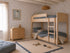 A cozy children’s room features light wood bunk beds, blue bedding, a matching dresser, a beige rug with blue trim and toys, plus Beach Vibes Wallpaper in Blue; sunlight pours in through a window with sheer curtains.