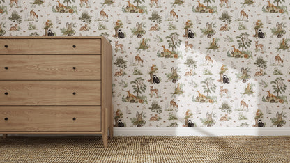 A wooden dresser stands on a woven carpet beside a wall covered in Tales Beneath The Trees Wallpaper Cream, featuring playful giraffes, lions, monkeys, and trees. Sunlight highlights the vibrant colours of this high-quality animal-themed wallpaper.