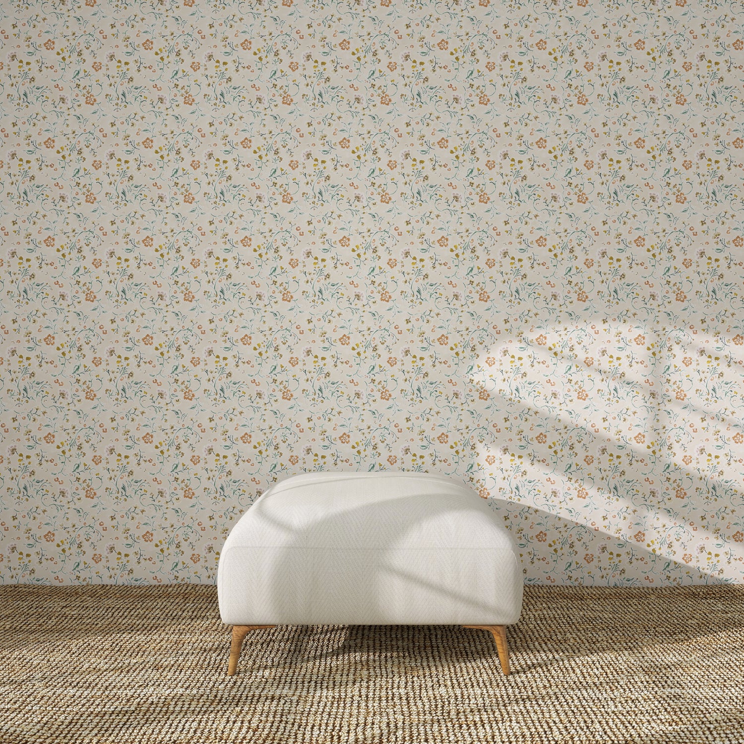 A white upholstered ottoman stands on a beige rug in front of Terra Bloom Wallpaper Sample. Sunlight casts shadows over the ottoman and accentuates the colour and floral design of the wallpaper.