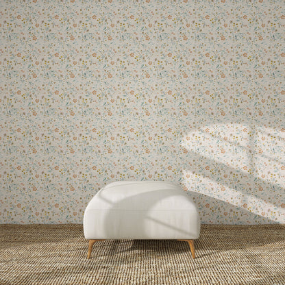 A white upholstered ottoman stands on a beige rug in front of Terra Bloom Wallpaper Sample. Sunlight casts shadows over the ottoman and accentuates the colour and floral design of the wallpaper.