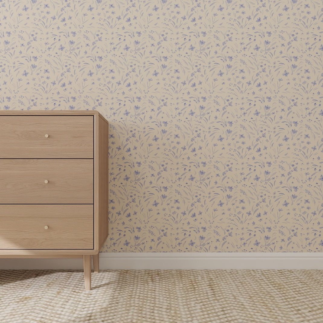 A wooden dresser with three drawers stands against a beige wall decorated with Butterfly Meadowland Wallpaper Repeat Pattern Cyan. The floor features a light, textured carpet, adding playful charm to the tidy, minimalistic setting.