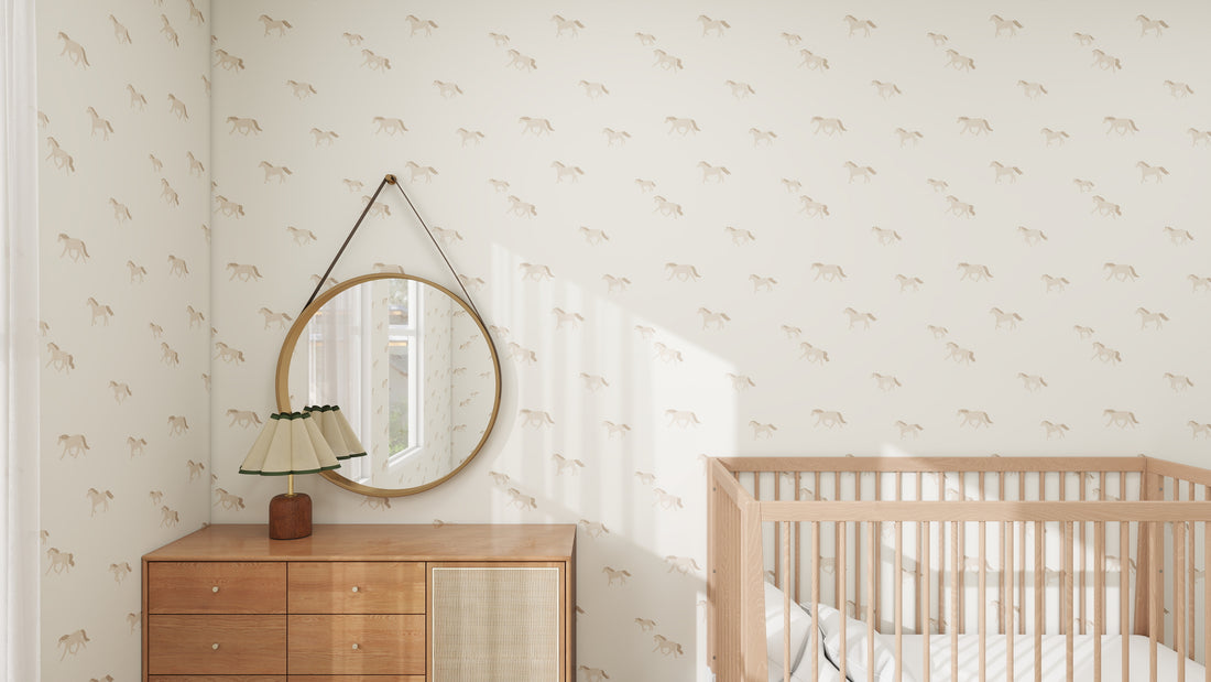 A minimalist nursery features calming and stylish Winter Wild Horses Wallpaper Repeat Pattern by munks and me, a wooden crib, and dresser with a retro lamp. A round mirror with a leather strap hangs above the dresser, reflecting light from a window.